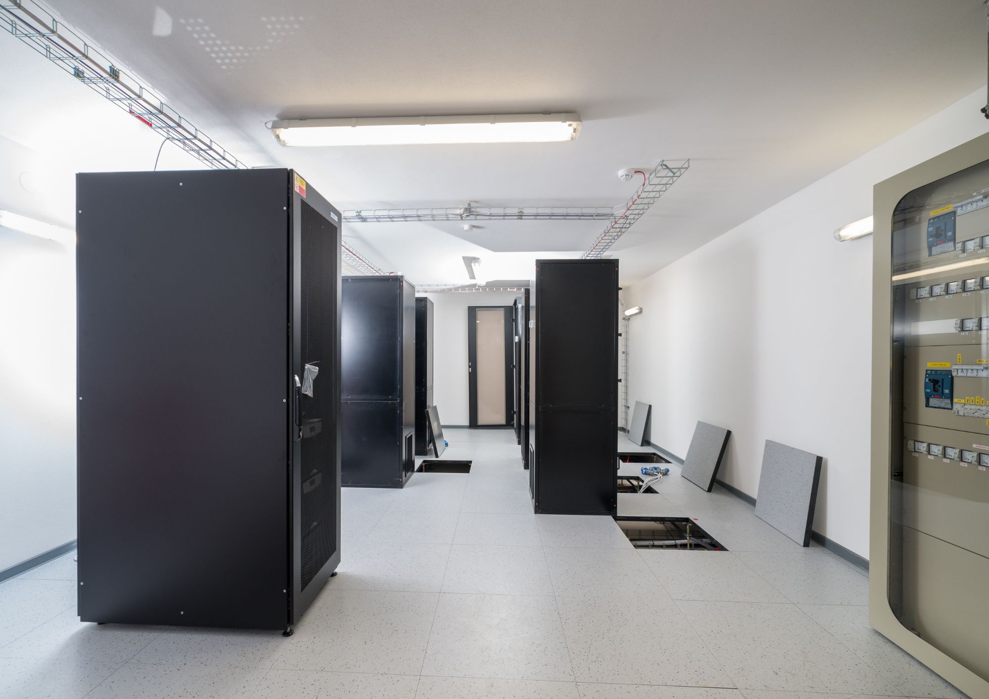 Ruang server modern dengan rack server dan raised floor sebagai solusi infrastruktur IT enterprise.